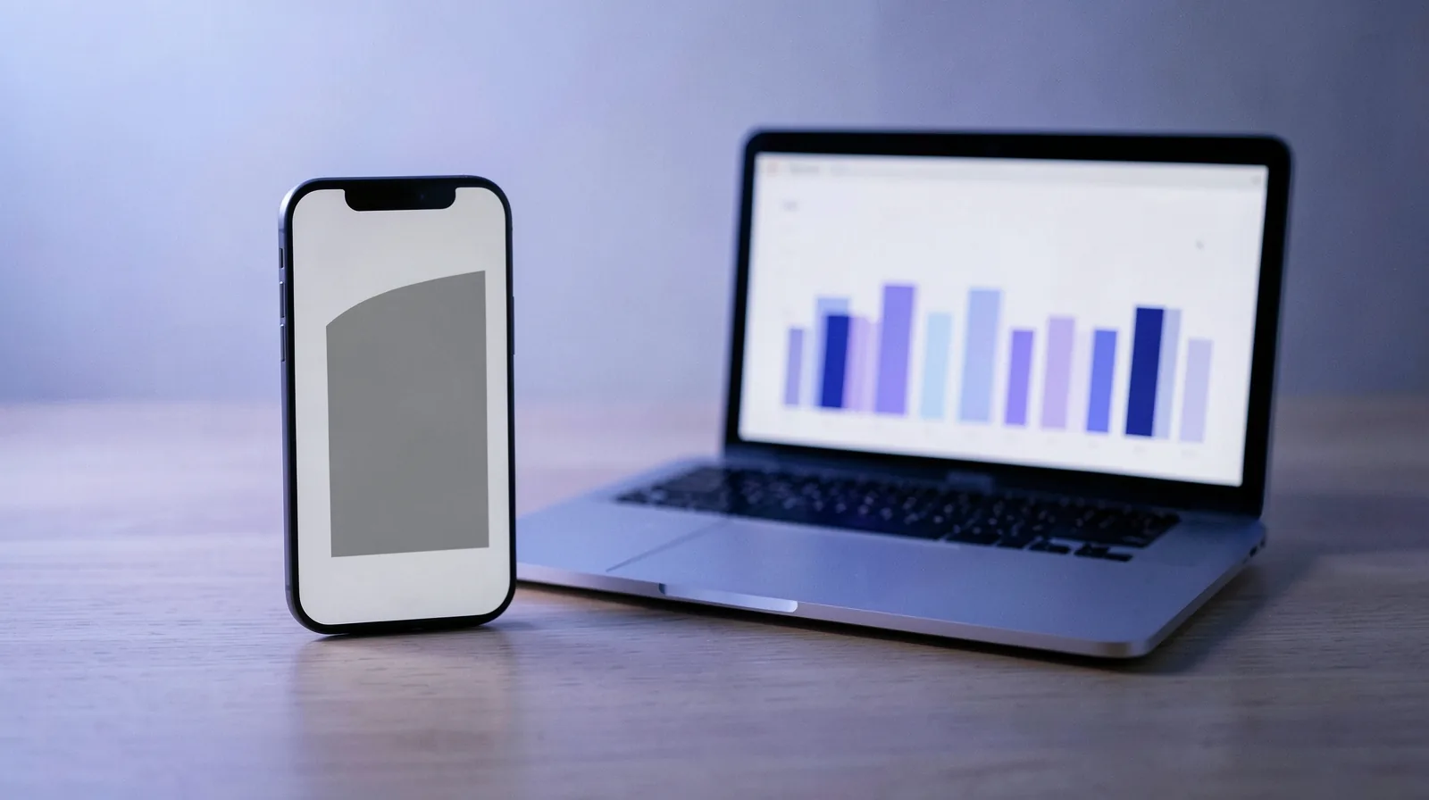 Celular de pé com uma página abstrata carregada ao lado de um notebook com painel de barras de desempenho