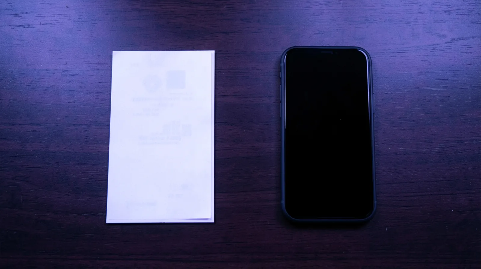 Dois recibos impressos de tamanhos diferentes ao lado de um cartão de crédito e um celular sobre uma mesa de escritório